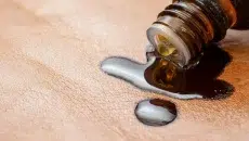 A small bottle of castor oil spilled on a piece of cloth to make a castor oil pack.