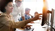 A woman in a white shirt showing someone how to find old addresses on a computer.